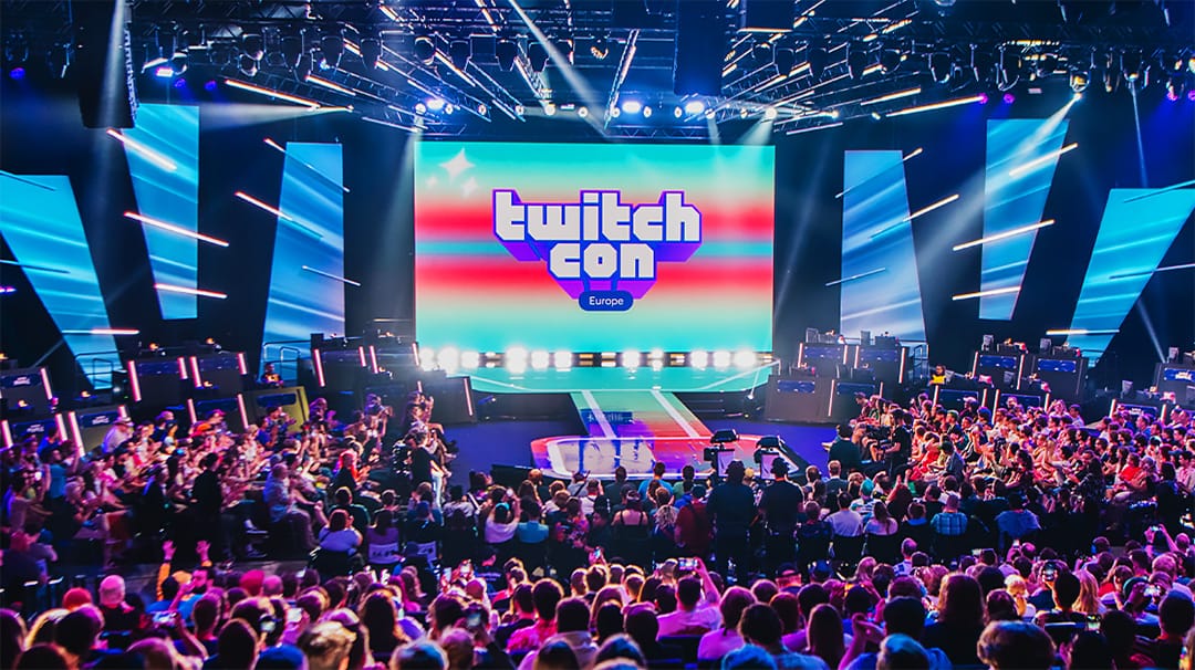 Photo du main stage de la TwitchCon Europe. La salle est pleine et donne sur un grand écran géant ainsi qu'une scène.