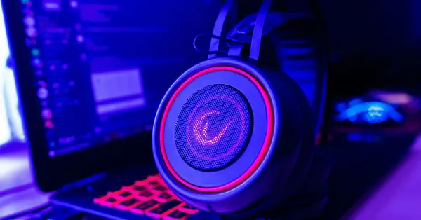 Un casque audio typé gaming, noir et rouge, est posé sur un laptop ouvert sur Discord.